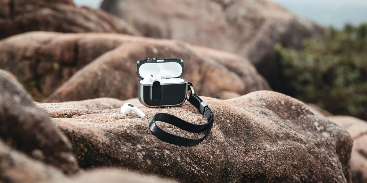 MAGEASY Odyssey rugged AirPods Pro 3 case on a rock with wrist strap attached and AirPods displayed