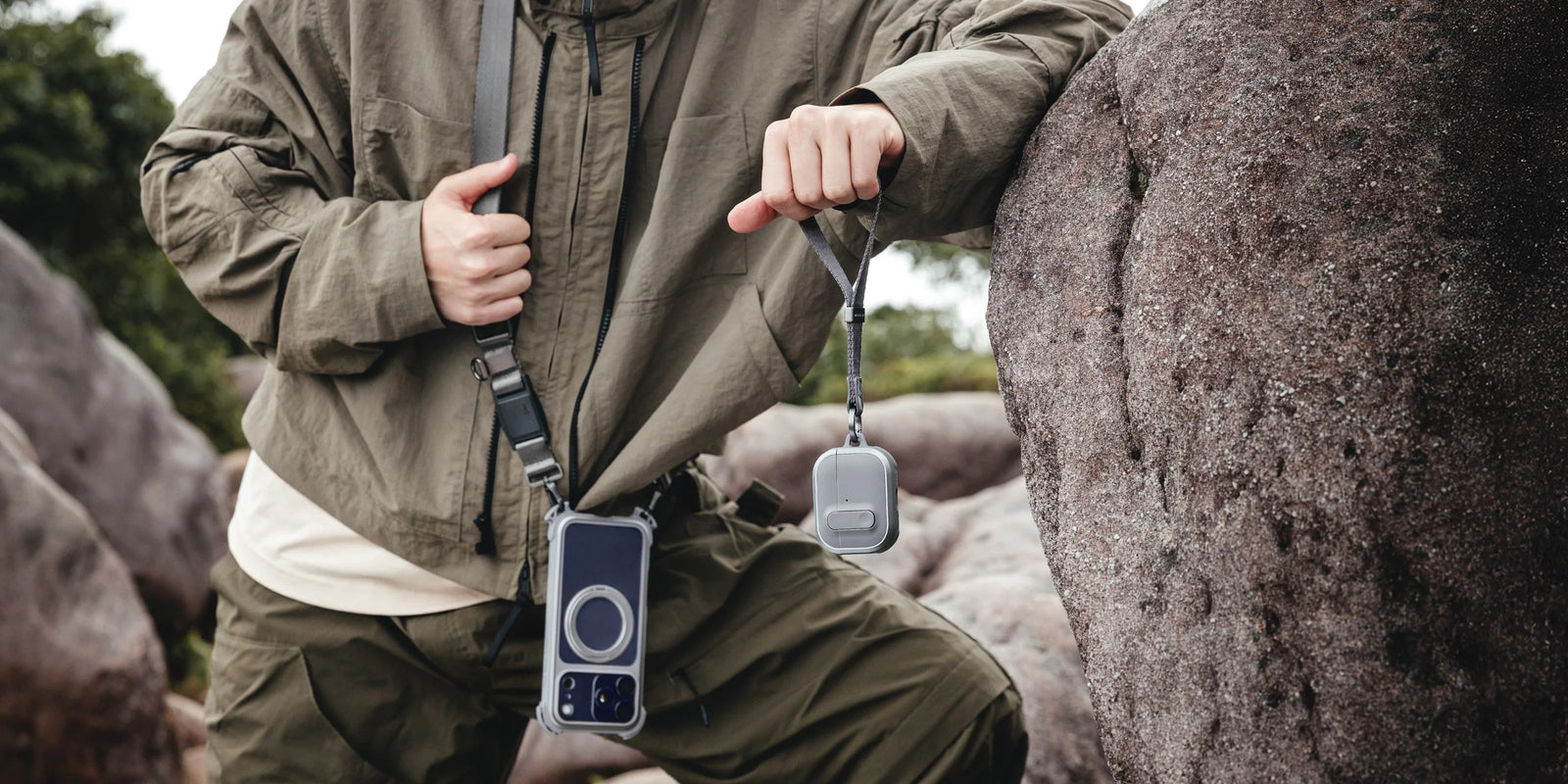 MAGEASY Odyssey rugged AirPods Pro 3 case hanging by the strap beside a rock for adventure travel